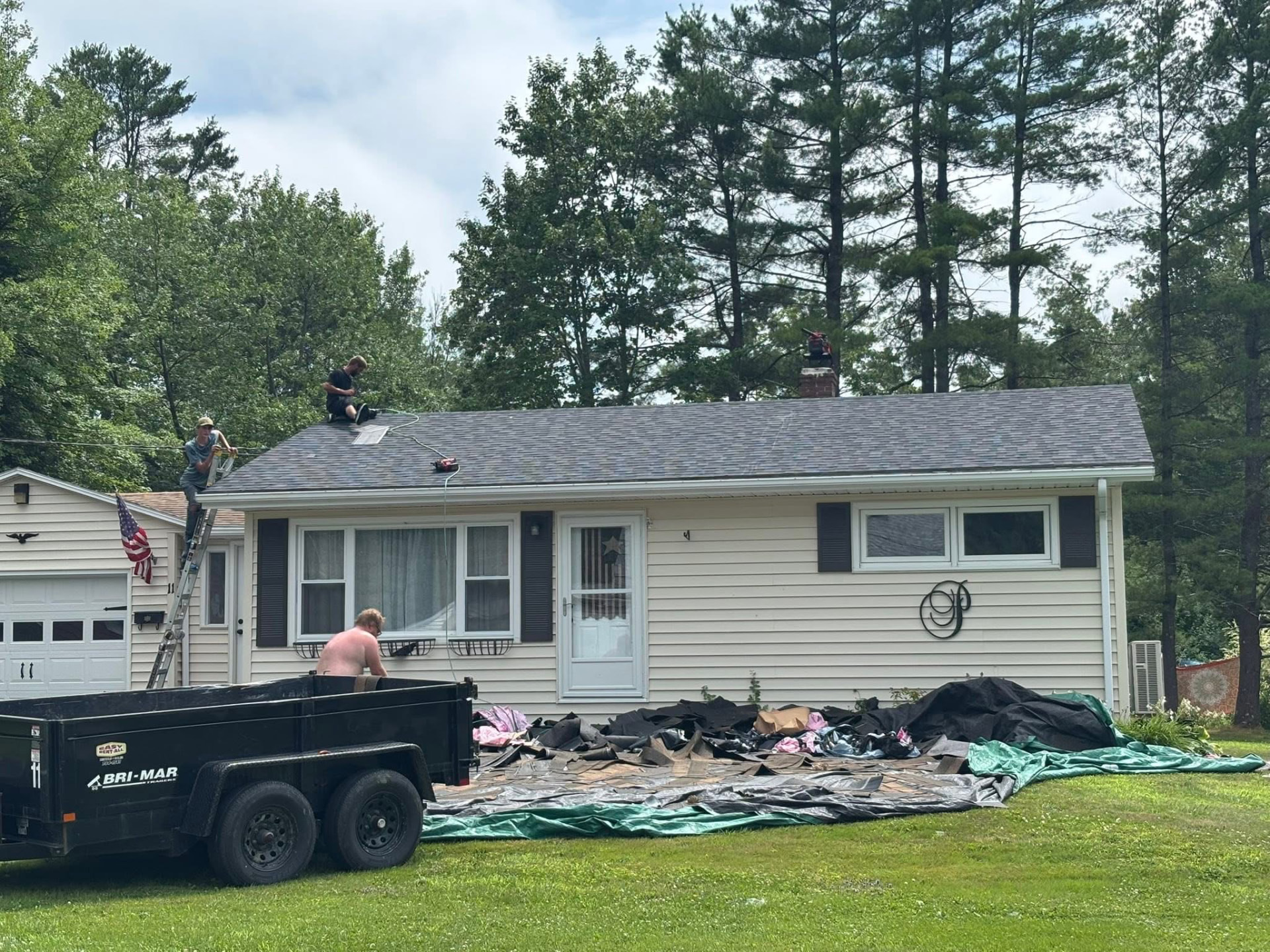 Roofing crew tearing off old shingles on a residential home